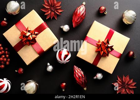 Christmas composition. Christmas gifts boxes wrapped red ribbon, striped baubles, decorations on dark black background. Flat lay, top view. Stock Photo