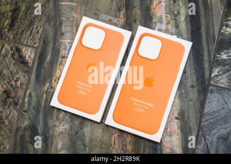 Two Apple Computers Silicone orange cases for the latest iPhone 13 Pro smartphone telephone isolated on stone background Stock Photo