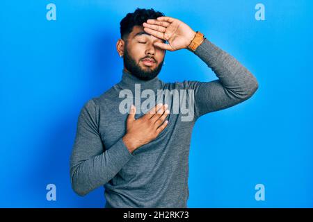 Arab man with beard wearing turtleneck sweater touching forehead for illness and fever, flu and cold, virus sick Stock Photo