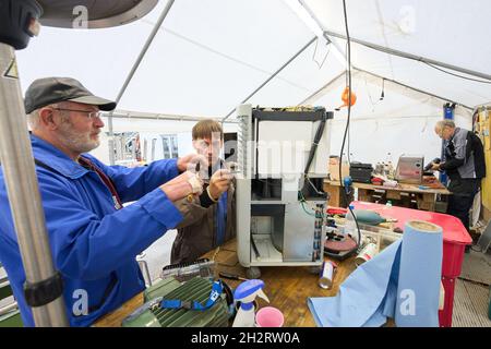 Walporzheim, Germany. 21st Oct, 2021. The two "Elektroseelsorger" Thomas (l) and Iwer repair a construction dryer in the workshop tent. The donation-funded and volunteer-based association "Elektroseelsorge(r)" consists of around 220 electricians, telecommunications technicians and other volunteers from all over Germany. They get muddy and once sodden electrical appliances such as drills, cordless screwdrivers, kitchen machines and heaters working again. (To dpa: ""Elektroseelsorge(r)" in the Ahr Valley: "Festival of Lights" as a sign of hope") Credit: Thomas Frey/dpa/Ģ����ý Live News Stock Photo