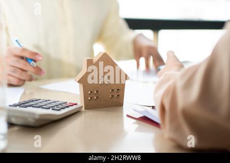 Client signs home loan document to buy homes with real estate property agent or lawyer. Real estate agent and customer signing contract to buy a house Stock Photo
