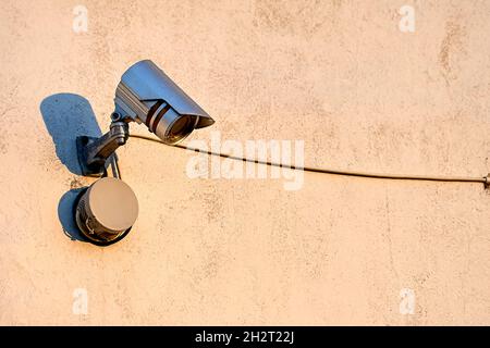 A surveillance camera is hanging on the wall of the house Stock Photo