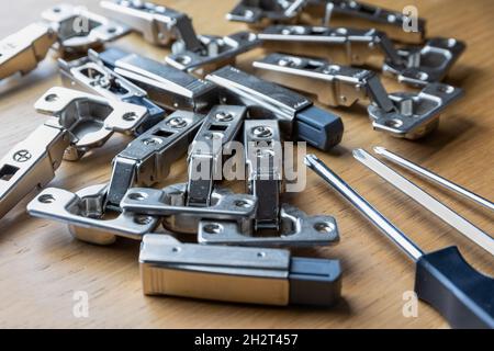 A pile of soft close cabinet door hinges and screwdrivers Stock Photo