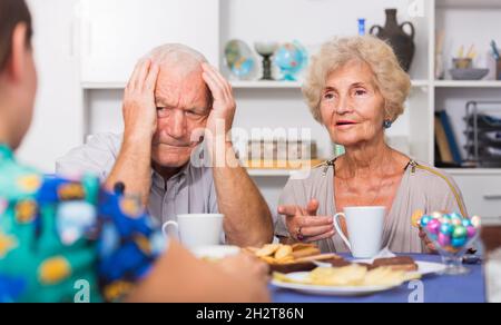 Stressed senior couple having conversation with female Stock Photo