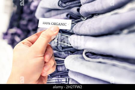 Organic jeans, ethical denim pants. Stack of clothes in store shelf. Label and tag. Sustainable retail fashion and quality product. Stock Photo