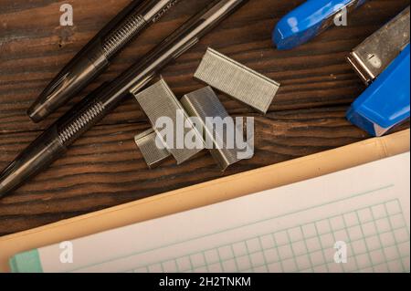 Office stapler, stapler staples and white paper on the table, close-up, selective focus Stock Photo