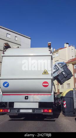 Trash truck collecting urban paper dumpster. Smart hydraulic system rise blue container automatically from side Stock Photo