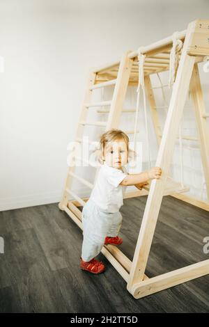 Baby girl play with developmental wooden structure at home or kindergarten or daycare center Stock Photo