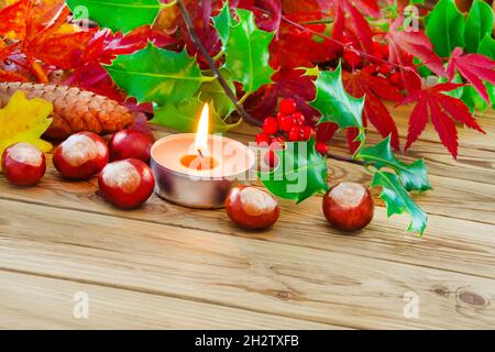 Natural Autumn decoration and burning candle on wooden background Stock Photo