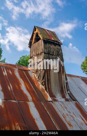 View of old house roof, covered with rusty steel sheets and chimney Stock Photo