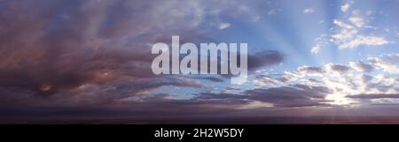 Panorama of dramatic sky at sunrise or sunset. Abstraction of blurred clouds and the sun breaking through the clouds Stock Photo