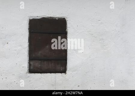 window with closed metallic shutter on old house wall Stock Photo