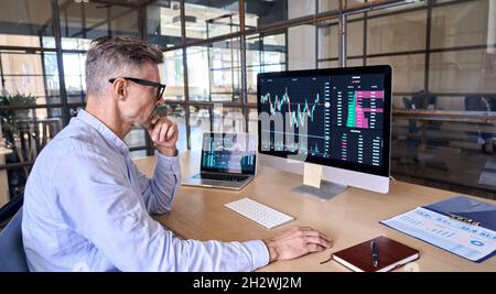 Busy crypto trader using computer analyzing digital stock market trading graph. Stock Photo