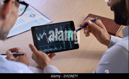 Trader consulting investor showing crypto trading chart using digital tablet. Stock Photo