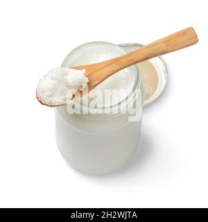 Single glass jar and a wooden spoon with coconut oil isolated on white background Stock Photo
