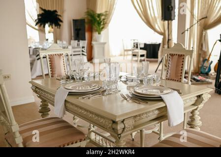 Place setting with menu and plates  at elegant shabby chic table. Beautiful table set for an event party or wedding reception . Restaurant interior. Stock Photo