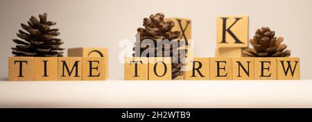 Time to renew was created from wooden cubes. Pine cones business concept. Stock Photo