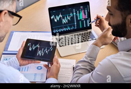 Two traders brokers stock exchange investors discussing crypto trading charts. Stock Photo