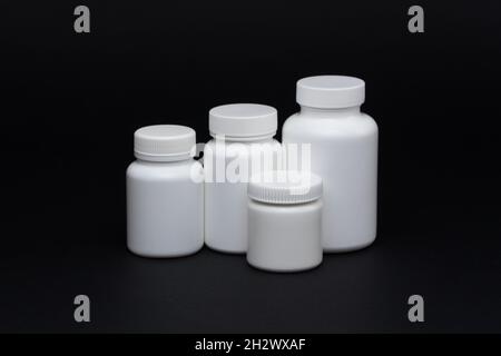 White plastic pill jars on a black background. Isolated Stock Photo