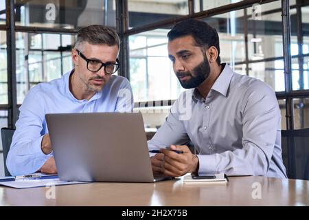 Two business men analysts discussing data management using laptop computer. Stock Photo