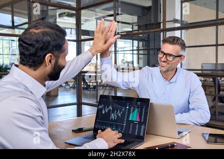 Two happy successful diverse traders investors giving high five. Stock Photo