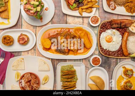 Top view image of a set of Colombian food dishes, with valluna cutlet, empanadas, paisa tray, prawn cocktail, fried patacones, shredded meat and guaca Stock Photo