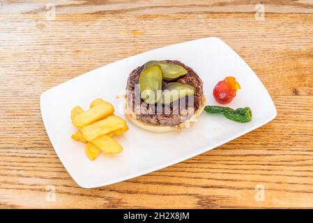 Beef Burger with Argentinian Chimichurri Sauce, Pickled Pickles, Homemade French Fries, and Fried Green Peppers Stock Photo
