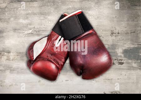 From above of pair of old red leather boxing gloves placed on shabby gray wooden background Stock Photo