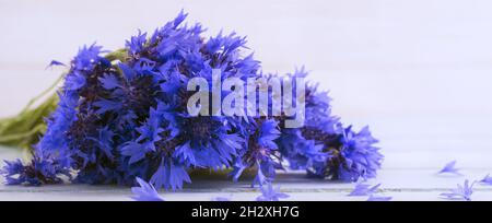 Bouquet of fresh cornflowers on a light wooden table background. Selective focus. Place for text Stock Photo