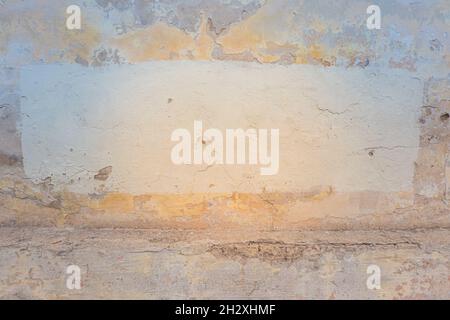 Old cracked abandoned shabby grunge yellow stucco plastered wall with fresh painted frame with copy space for text Stock Photo