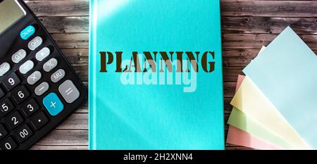 Marketing plan written on a turquoise notepad, office wooden table with a calculator and stickers Stock Photo