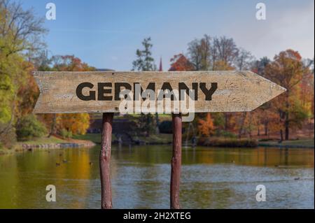 Germany wooden arrow road sign against autumn landscape background. Travel to Germany concept. Stock Photo