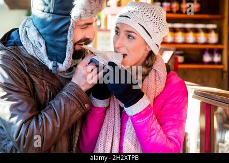 Woman and man eating rolls and sausage on Christmas Market Stock Photo