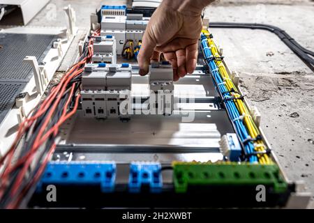 A male electrician works in a switchboard with an electrical connecting cable. Stock Photo