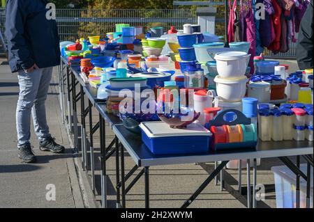Lots of colorful plastic storage containers and tubs on tables at a garage sale or flea market stall, selected focus, narrow depth of field Stock Photo