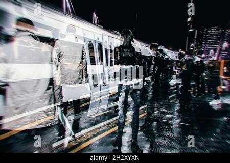 Multiple exposures of Commuters at Charing Cross railway station waiting to board a train standing in the rain, Cross processed colours Stock Photo
