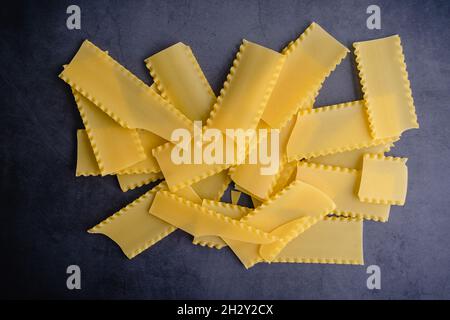 Broken Lasagna Noodles on a Dark Background: Uncooked lasagne noodles that have been broken into pieces Stock Photo
