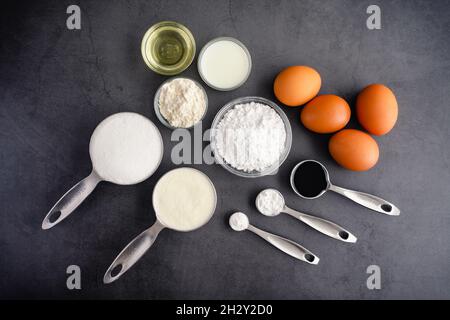 Ube Cake Roll Ingredients on a Dark Background: Ube extract, flour, eggs, and other raw ingredients Stock Photo