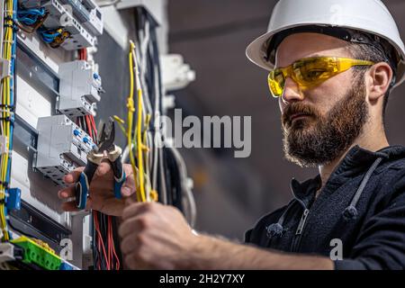 A male electrician works in a switchboard with an electrical connecting cable. Stock Photo