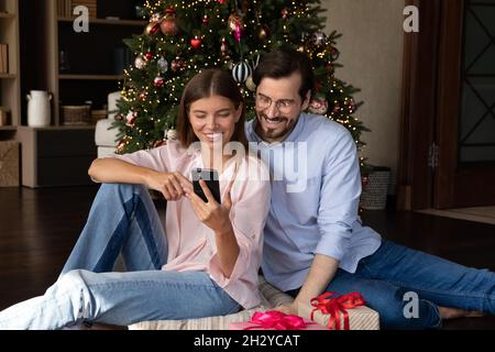 Happy relaxed family couple using smartphone at home. Stock Photo