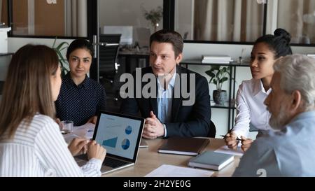 Diverse business partners sit at conference table talk develop strategy Stock Photo