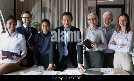 Smiling young male boss posing ahead of international work group Stock Photo