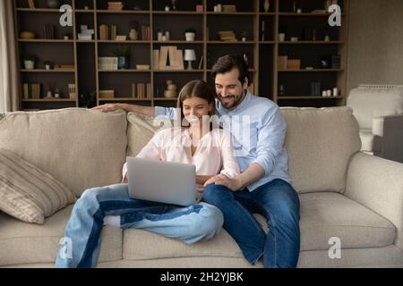 Happy young family couple using computer at home. Stock Photo