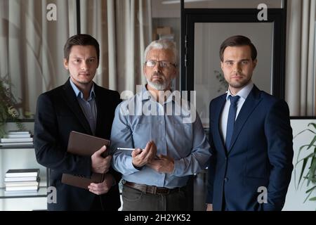 Portrait of aged businessman leader and two young men assistants Stock Photo