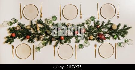 Flat-lay of Christmas table setting with white dinnerware and branches Stock Photo