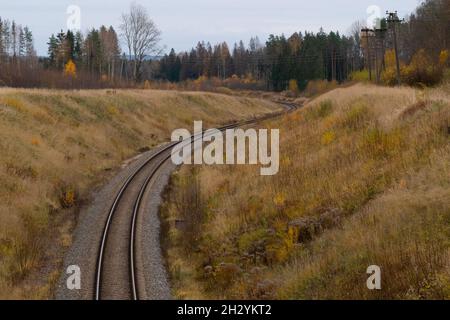 A winding railway track that leads down the hill through a forest valley in autumn. Stock Photo