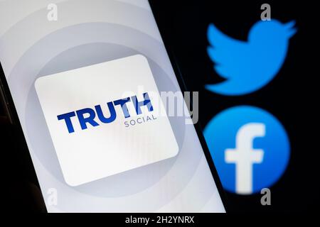 Truth Social app logo seen on the smartphone with blurred Facebook and Twitter logos on the background. New social media platform from Donald Trump. S Stock Photo