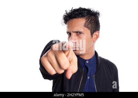 Young adult Latino young man pointing to camera, white background. Serious man pointing to camera with finger. Stock Photo