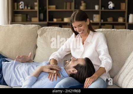 Happy young man resting on sofa with loving woman. Stock Photo