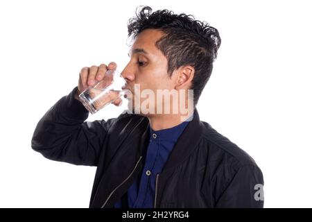 Man drinking water isolated on white background. Thirsty latin young man drinking water from transparent basin. Stock Photo